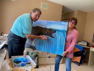 Mother, father, and baby holding a colorful painting outdoors
