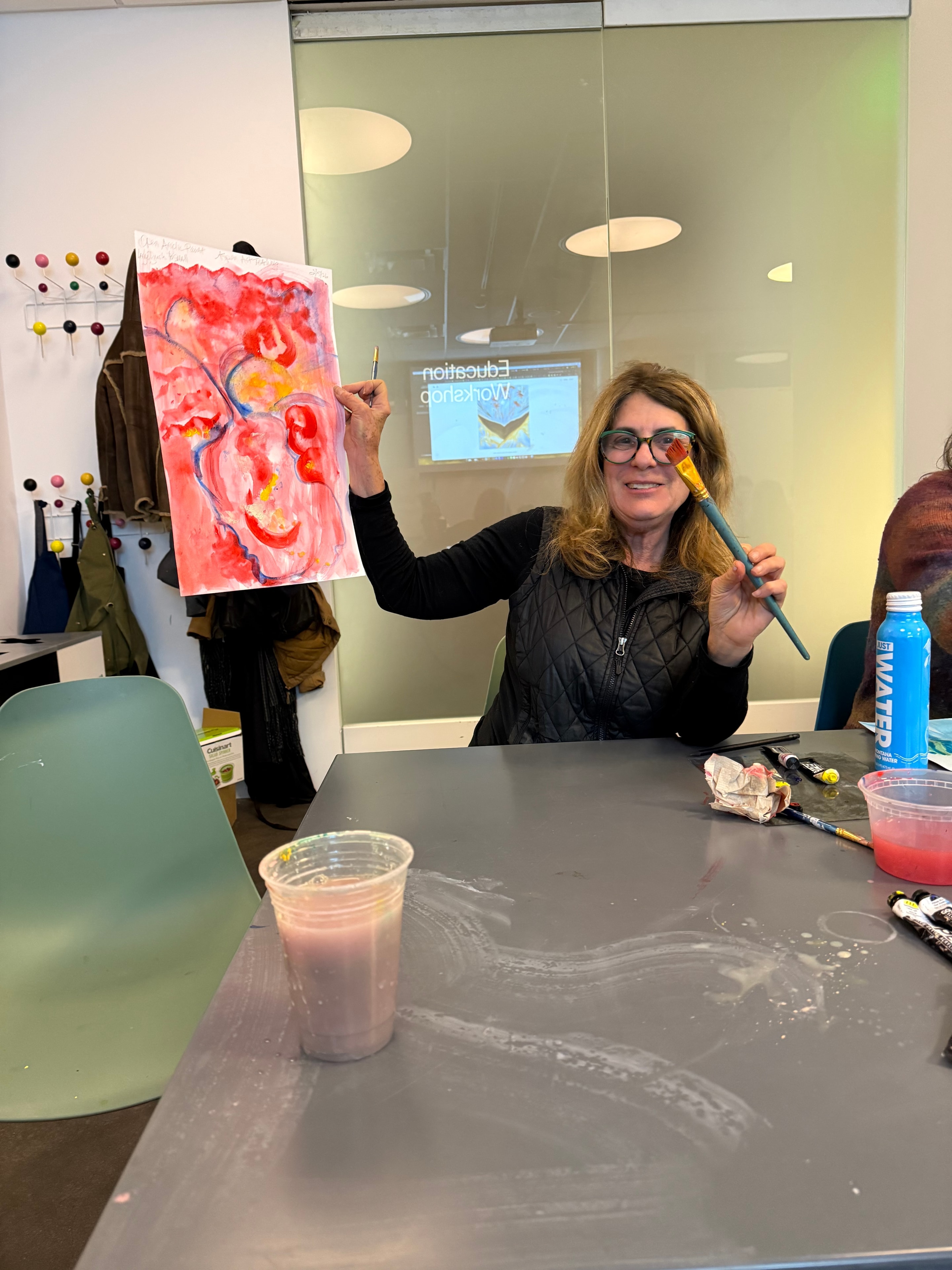 Lea Novgrad holding a paintbrush while painting — Aspen artist and instructor
